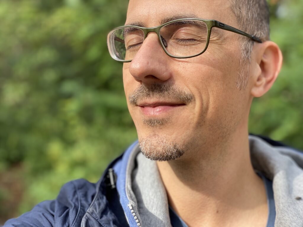 Mann mit Brille und geschlossenen Augen richtet das Gesicht in die Sonne.